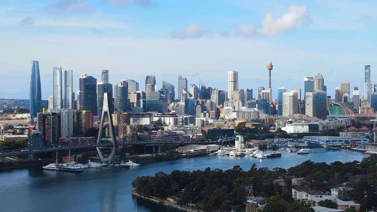 Aerial view of the Sydney harbour corridor near Anzac Bridge, with small ferries and wake trails visible on the water.